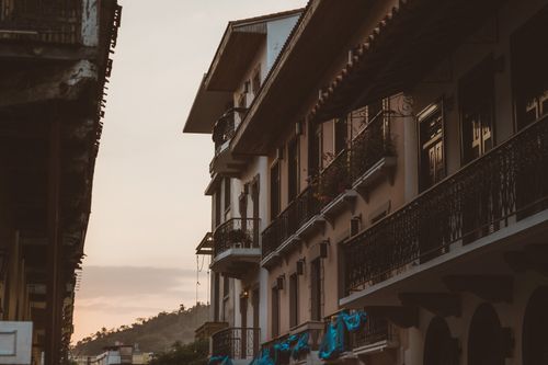 Free Elegant colonial-style buildings line a quiet street, captured in warm evening light. Stock Photo