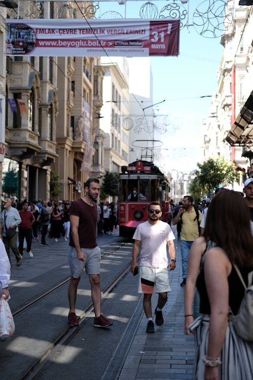 People walking down a city street with a tram