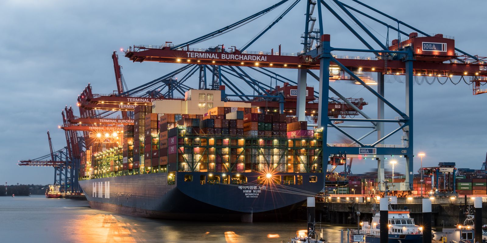Container ships moored at a busy port terminal in the evening