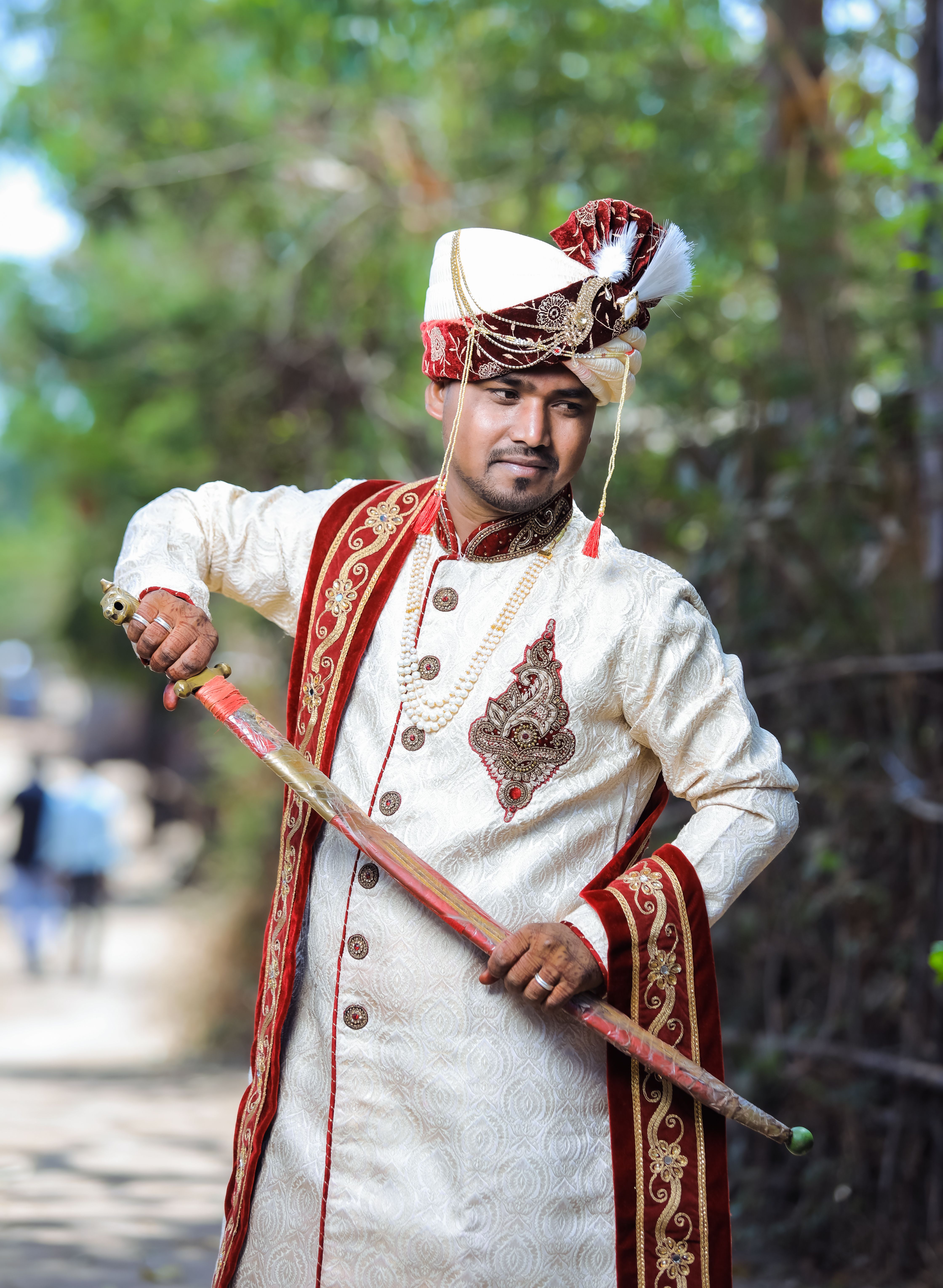 Man in Indian attire holding a sword in Surat, India, outdoors.
