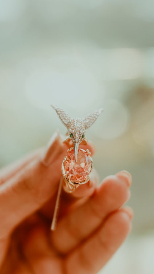 A person holding a small pink diamond ring