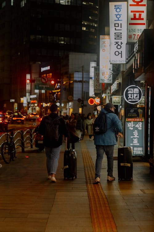 People walking down a city street with luggage