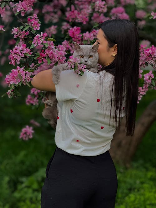 Free A woman holding a cat in front of a tree Stock Photo