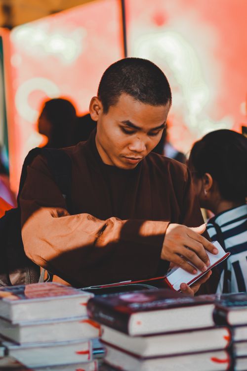 Free A young man immersed in reading at an urban bookshop setting. Stock Photo