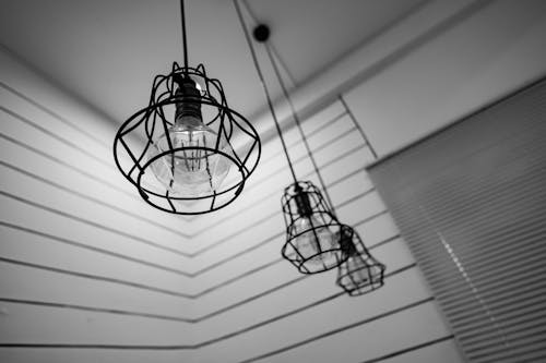 Black Steel Framed Round Pendant Lamp Indoors Near Window Blinds on Grayscale