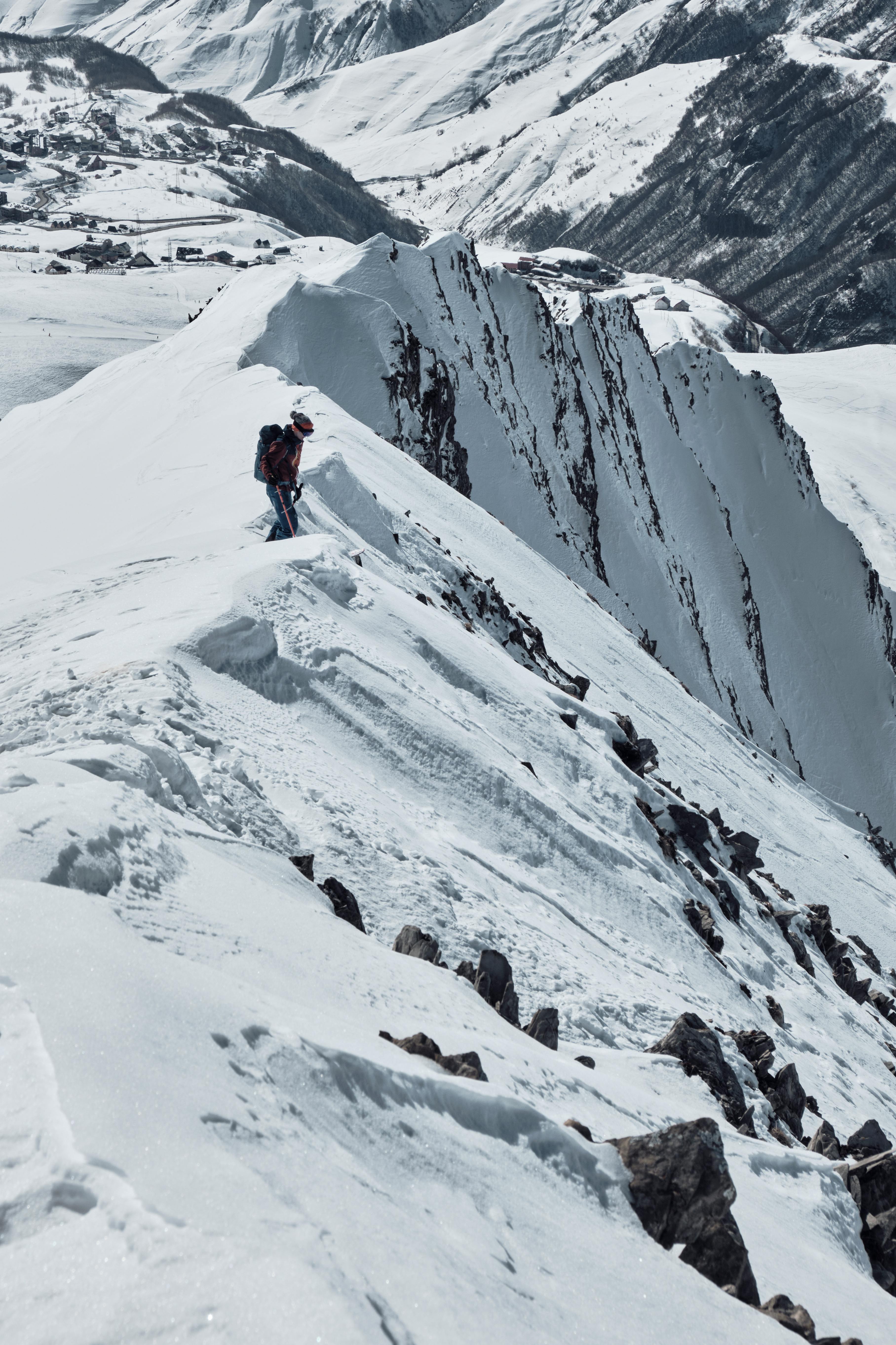 A mountaineer traverses a snowy ridge amid stunning mountain scenery. Perfect for adventure seekers.