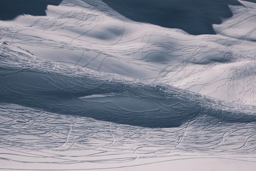 Captivating aerial shot capturing ski tracks on a snowy winter mountainside.