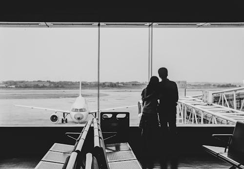 Free Lovers looking out the window at the airport terminal Stock Photo