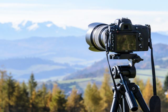 DSLR camera on a tripod aimed at a mountain landscape