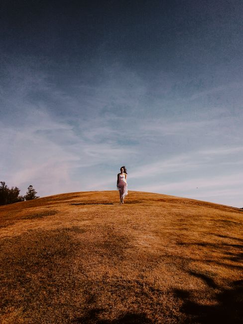 Solitary figure on a windswept grassy hill under a clear sky, evoking solitude and serenity.