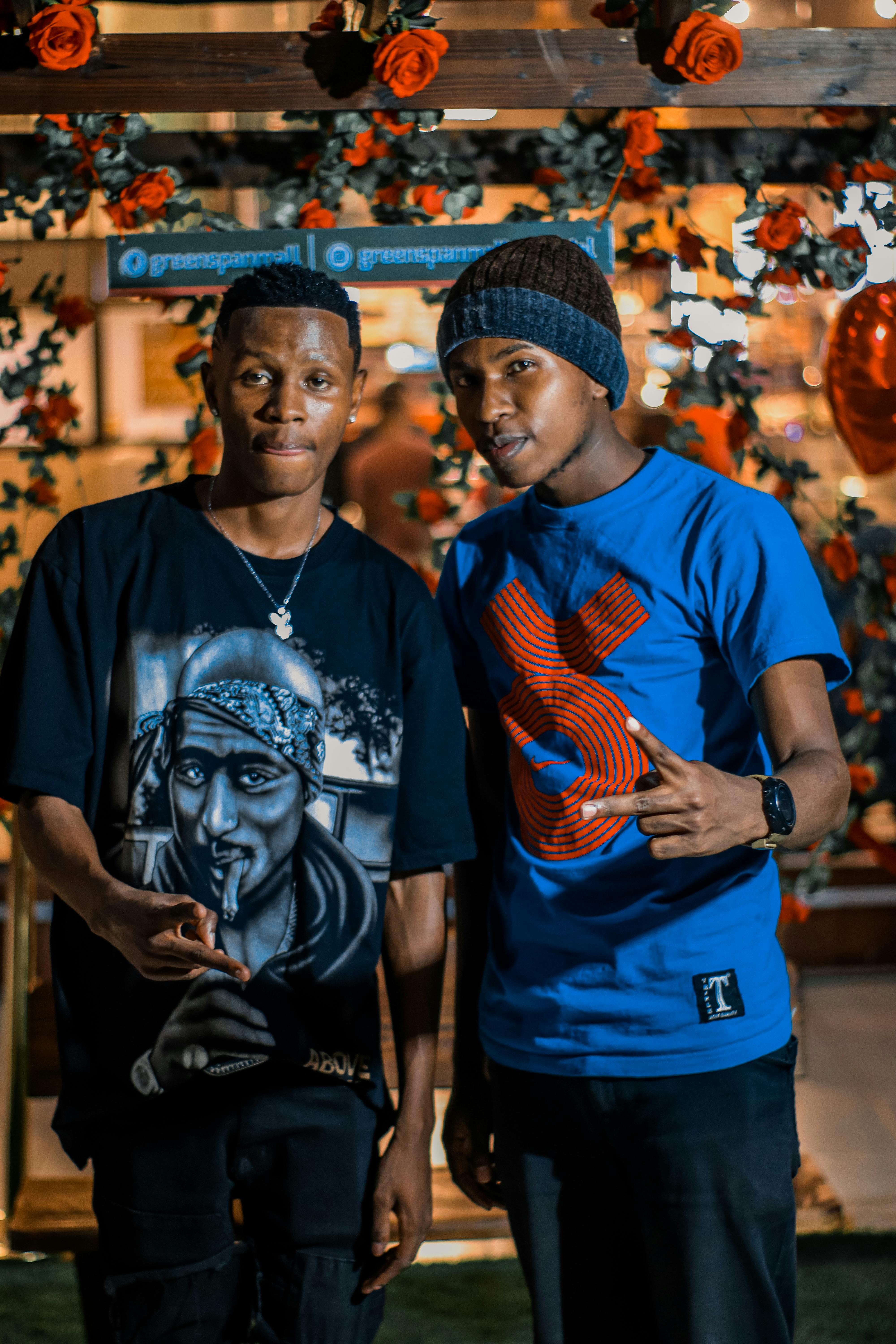 Two young men pose in trendy street fashion in Nairobi at night.