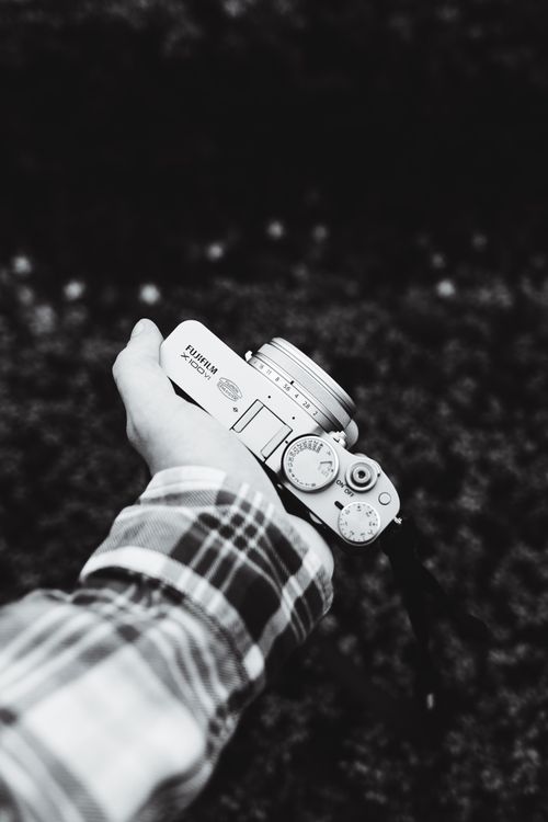 Free Black and white close-up of a hand holding a digital camera, outdoors. Stock Photo