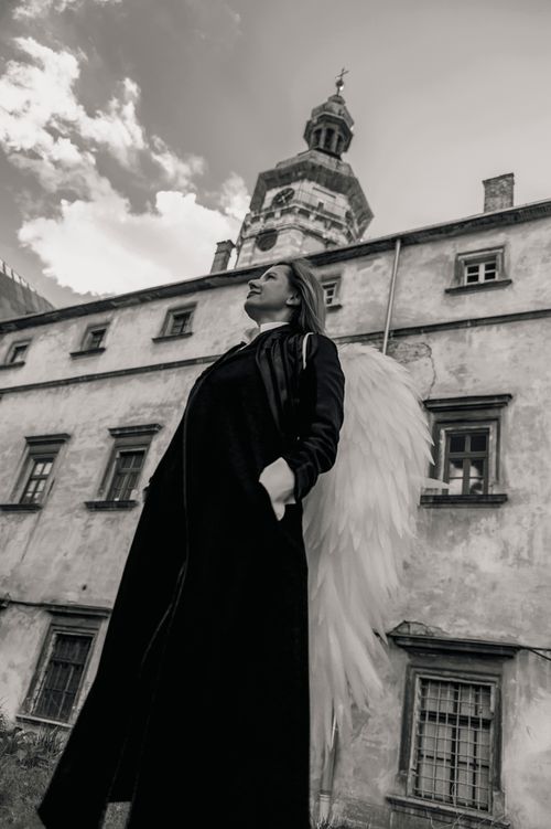 Free Urban fashion scene in Lviv with a model and angelic wings, blending elegance and architecture. Stock Photo
