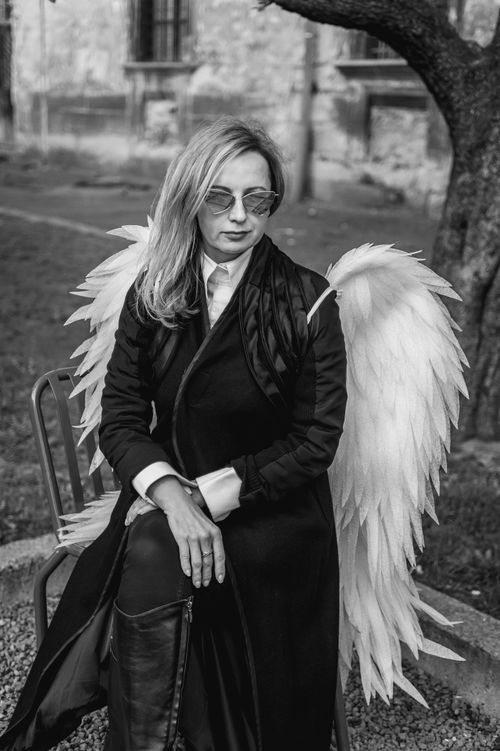 Free Black and white portrait of a woman with angel wings sitting outdoors in Lviv. Stock Photo