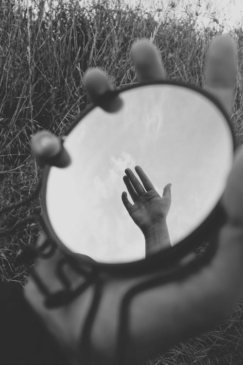 Reflection of a Hand Against the Sky in a Hand-held Round Mirror