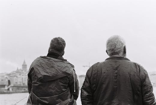 Two men in Istanbul overlooking Bosphorus Strait under overcast skies.