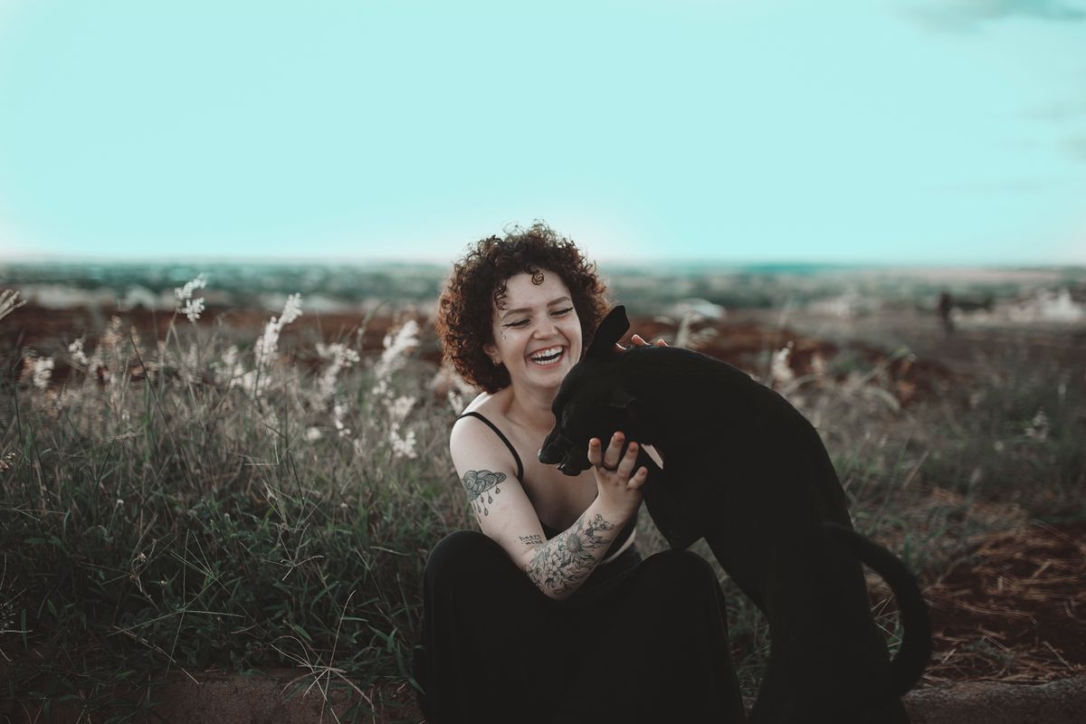Mulher sorrindo e fazendo carinho em cachorro
