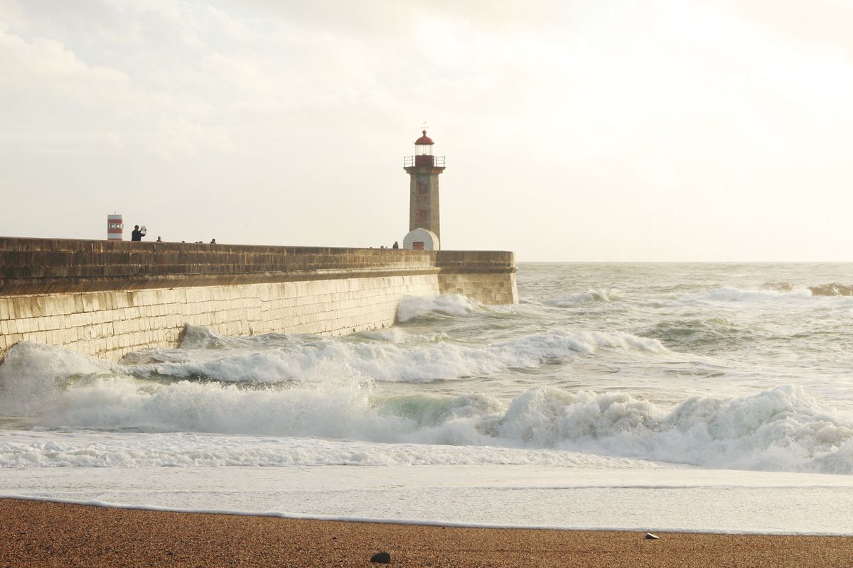 The Felgueiras lighthouse on the Foz do Douro breakwater with surf, Porto