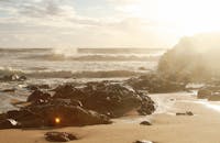 阳光明媚，海浪拍打着沙滩上美丽的岩石露头