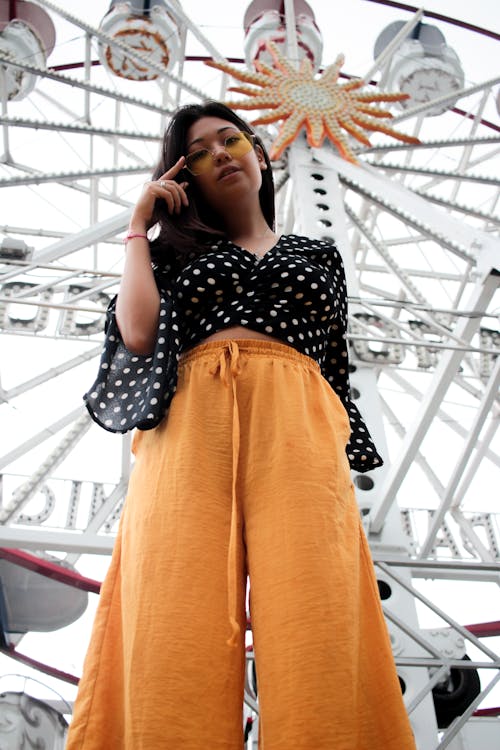 Low Angle Photo of Woman Standing Beside Ferris Wheel