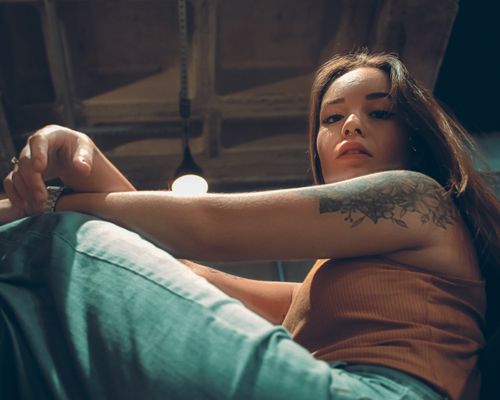 Free Stylish portrait of a woman with floral tattoo in an urban setting. Dramatic lighting and modern vibe. Stock Photo