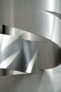 Abstract composition of intertwined metallic curves with light reflections.