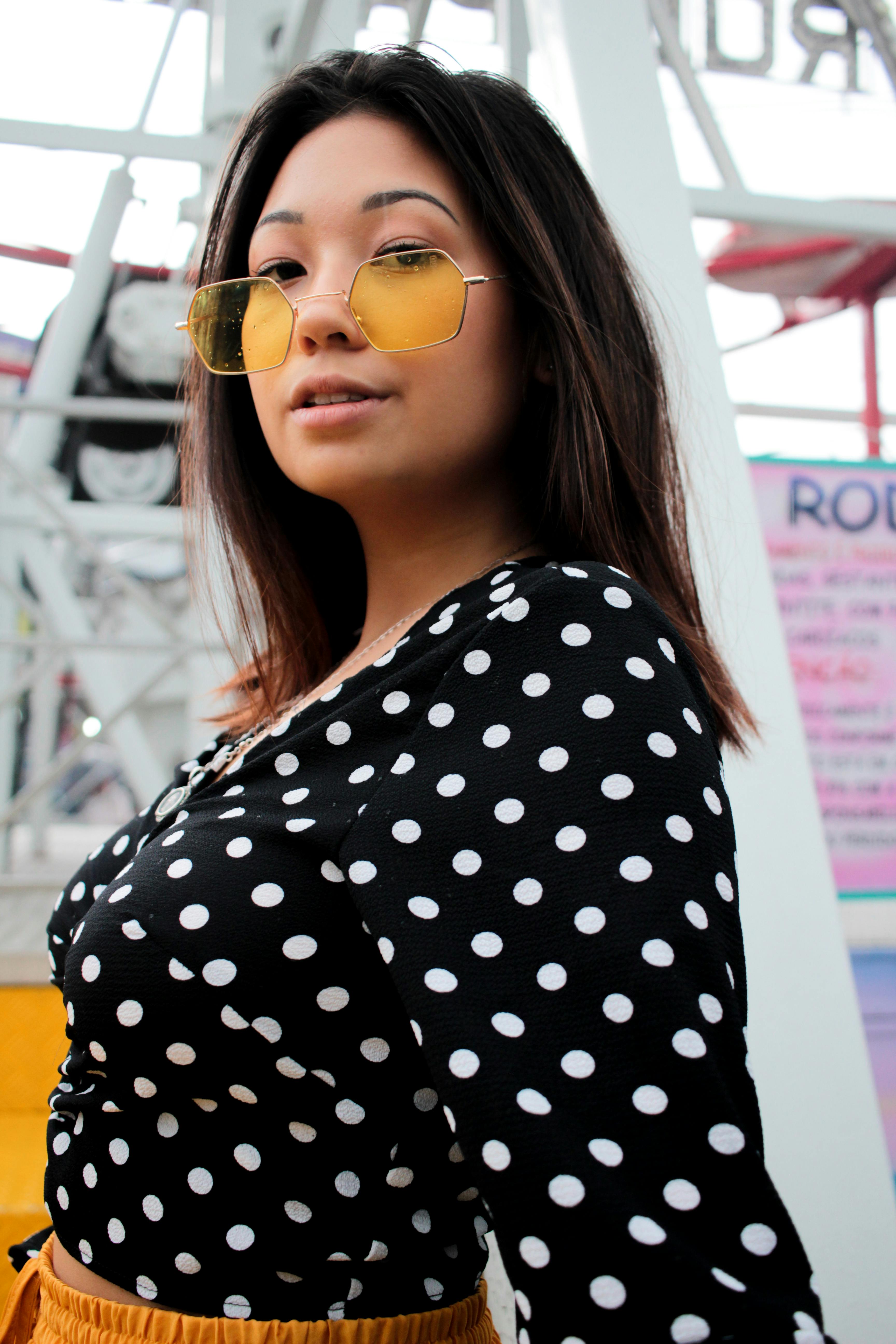一位穿着圆点连衣裙、戴着黄色太阳镜的时尚女士正在户外