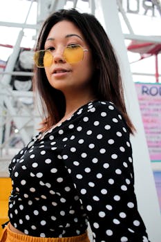 一位穿着圆点连衣裙、戴着黄色太阳镜的时尚女士正在户外