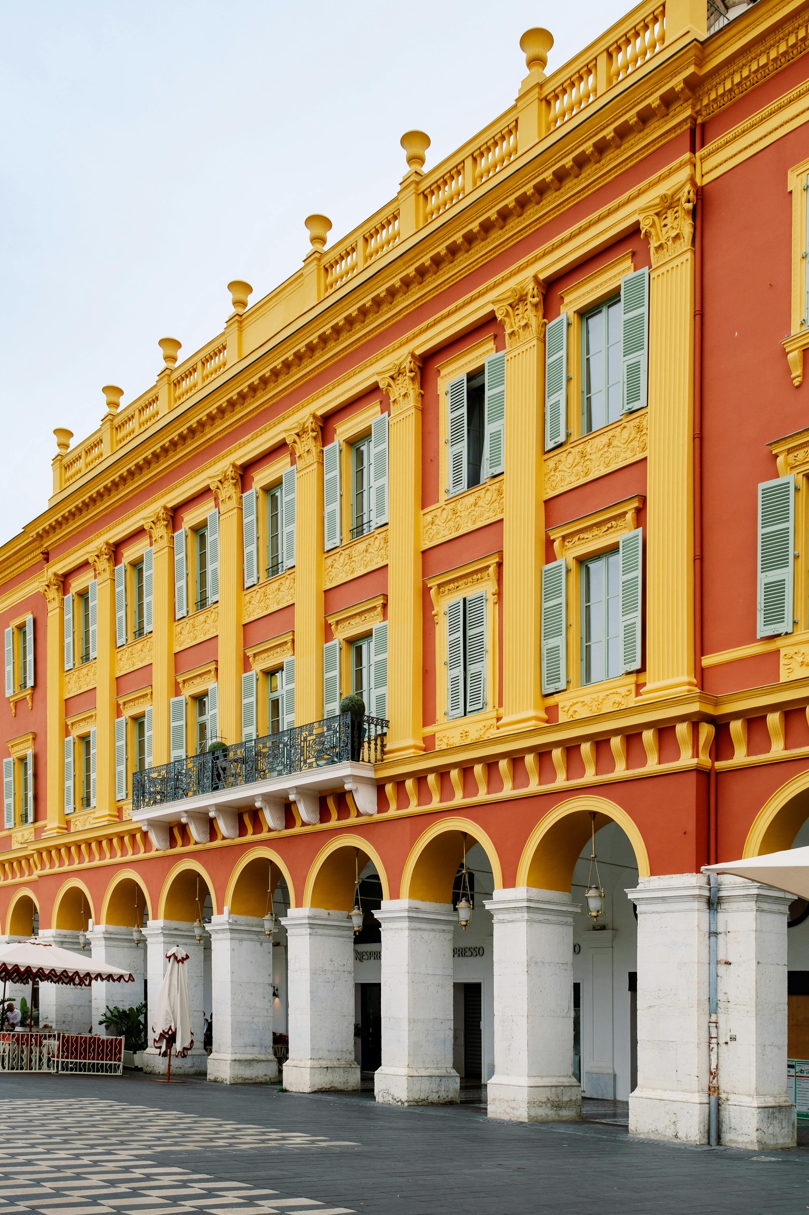 Colorful facade with arches and balconies in Massena Square, Nice, France.