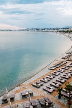 A stunning aerial shot of a serene Mediterranean beach resort with empty sunbeds and clear waters.