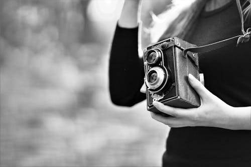 Grayscale Photo of Woman Holding Vintage Camera