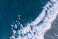 航拍镜头中，海浪拍打海岸线的景象令人惊叹，展示了大自然的美丽与力量