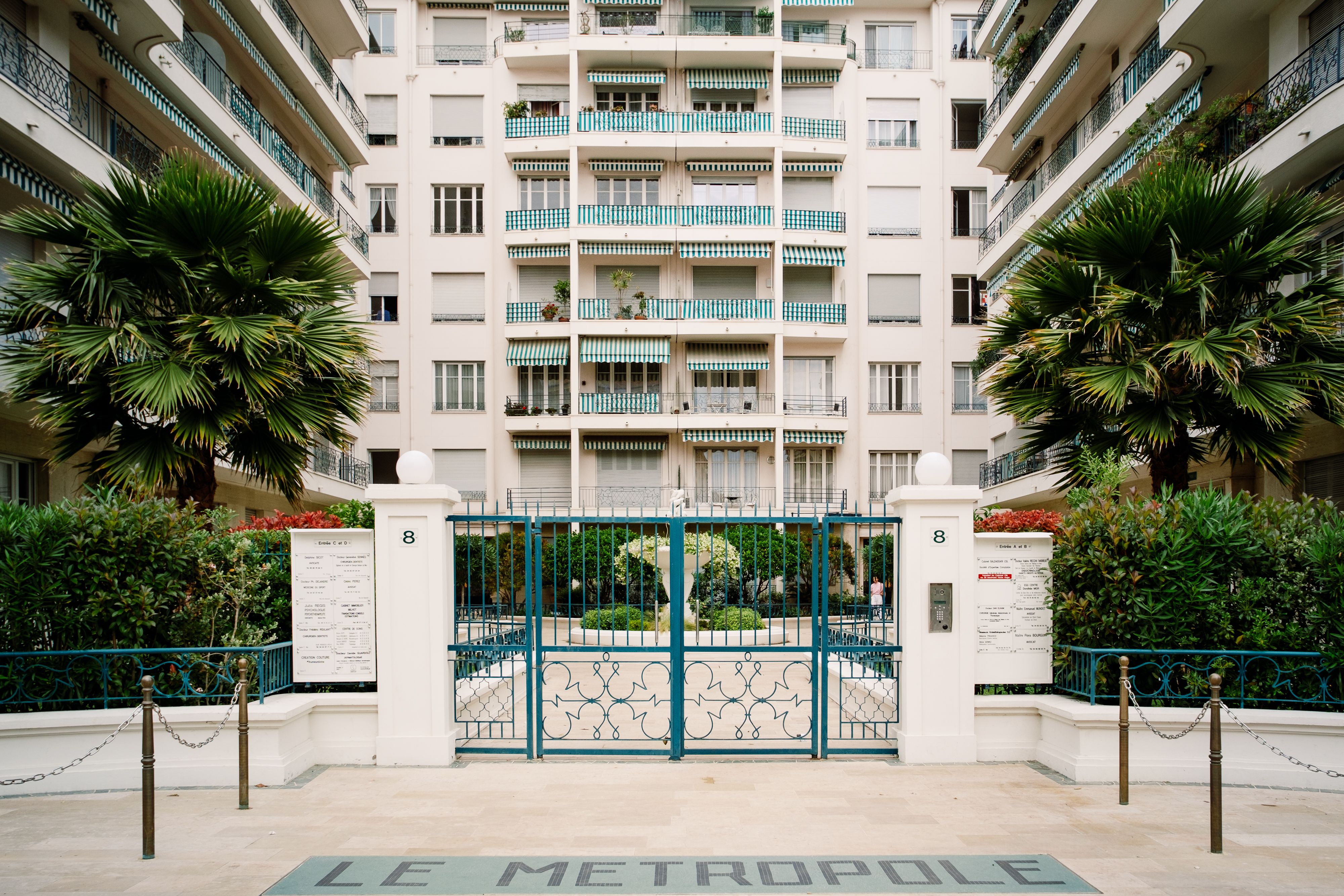 Sophisticated entrance of a gated community with tropical plants and decorative gate.