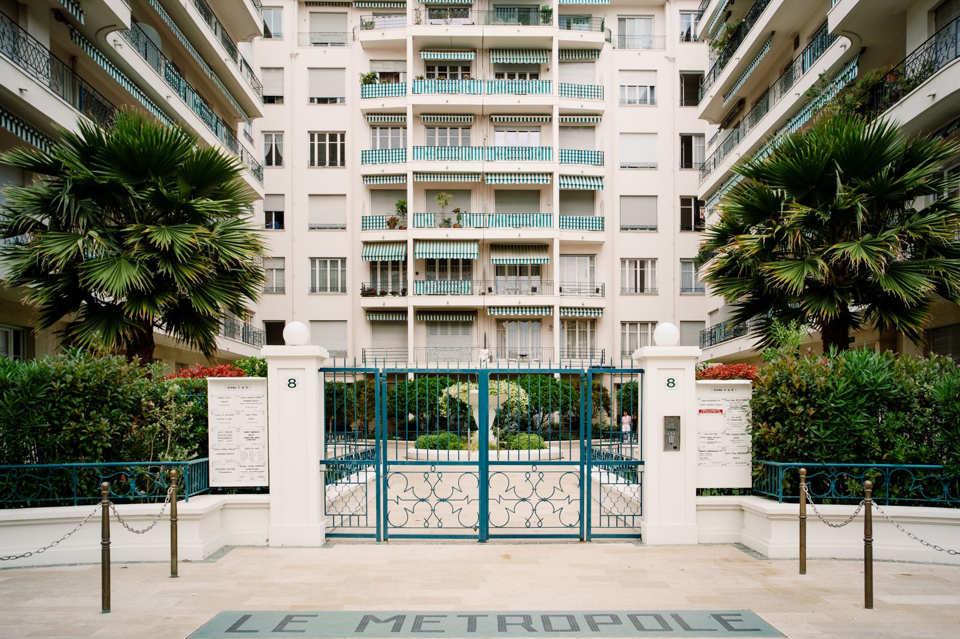 Sophisticated entrance of a gated community with tropical plants and decorative gate.