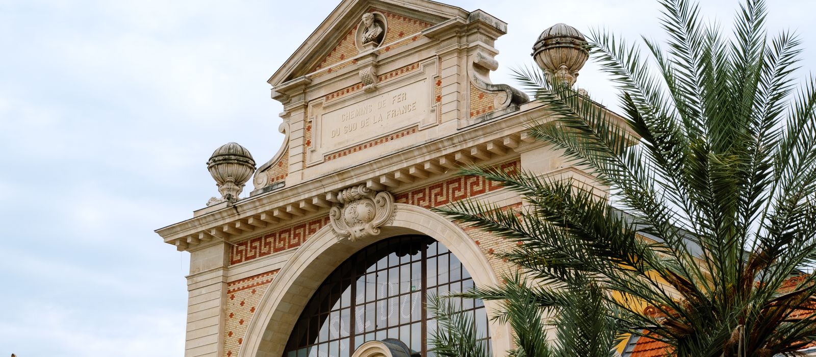 Classic French architecture with palm trees under a clear sky, highlighting intricate design and elegance. — flights from Lille to Nice