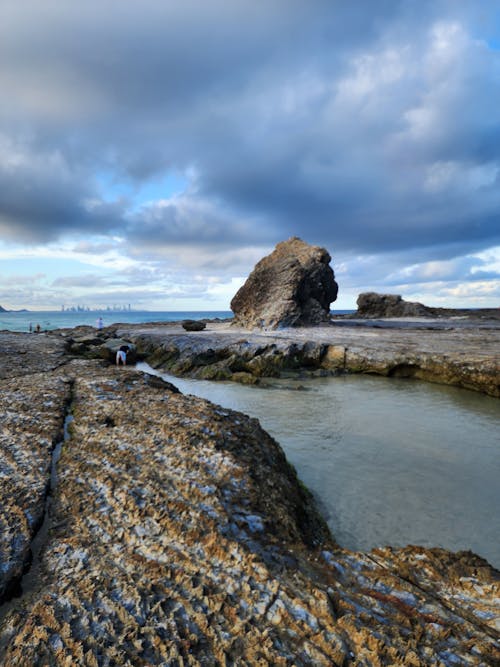 A rock formation on the beach with a cloudy sky