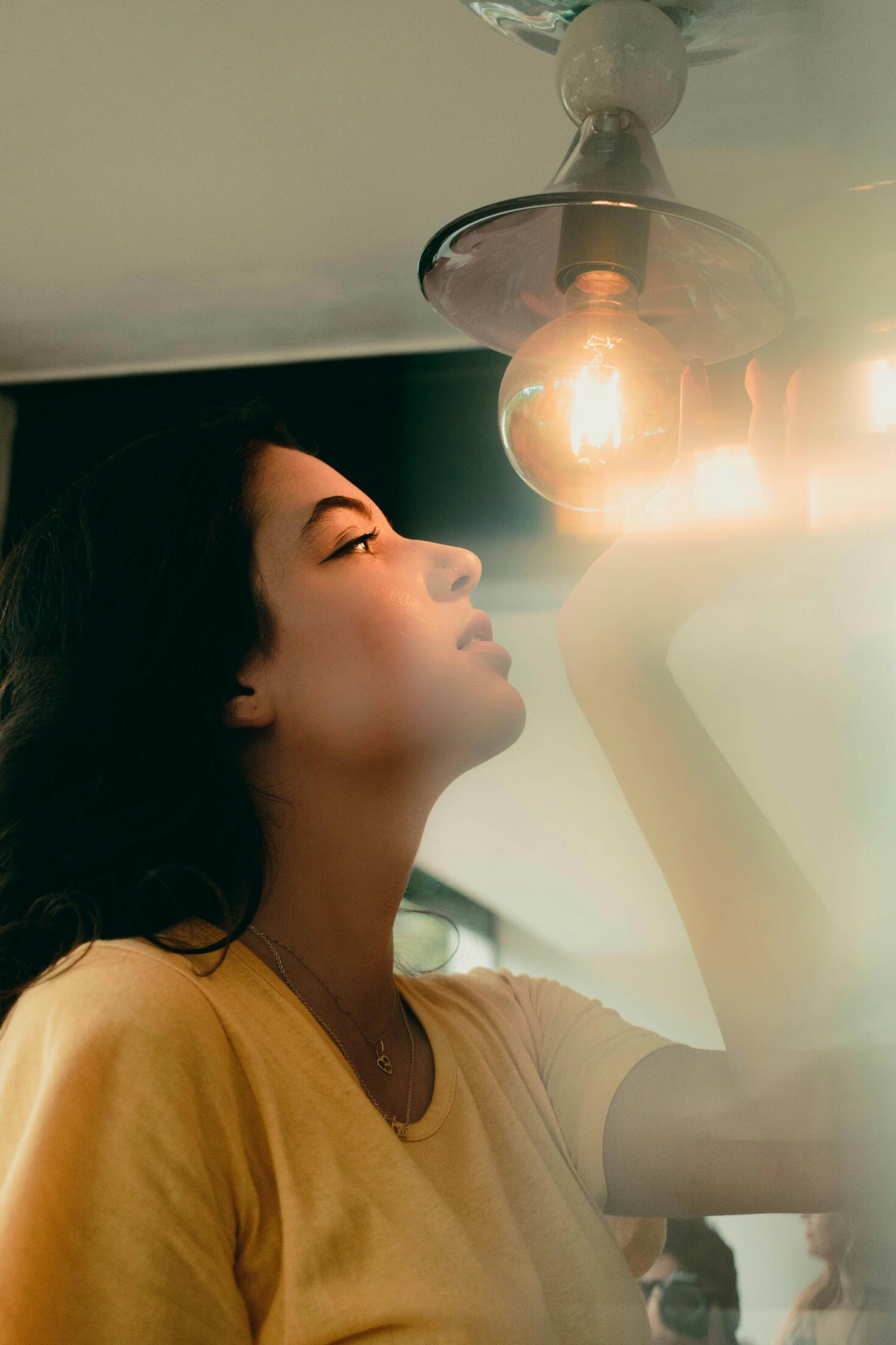 Woman About To Hold A Pendant Lamp · Free Stock Photo