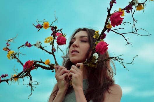 一名闭着眼睛的妇女在户外拿着一根装饰着彩色花朵的树枝