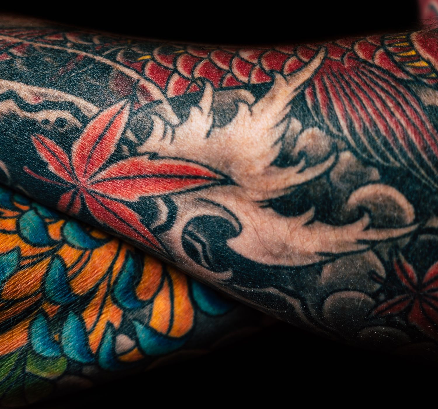 Detailed close-up of a sleeve tattoo featuring floral and abstract linework.
