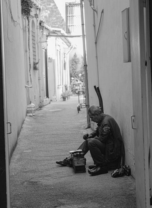 Free A man sitting on the ground in a narrow alley Stock Photo