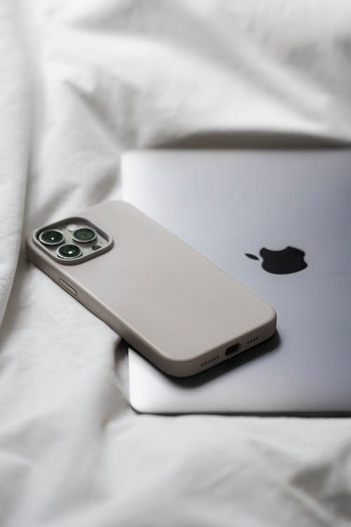 Free A white iphone 11 pro case sits on top of a bed Stock Photo