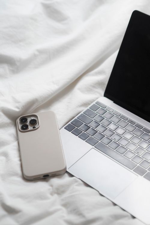 Phone and a Laptop Against White Sheets Background · Free Stock Photo