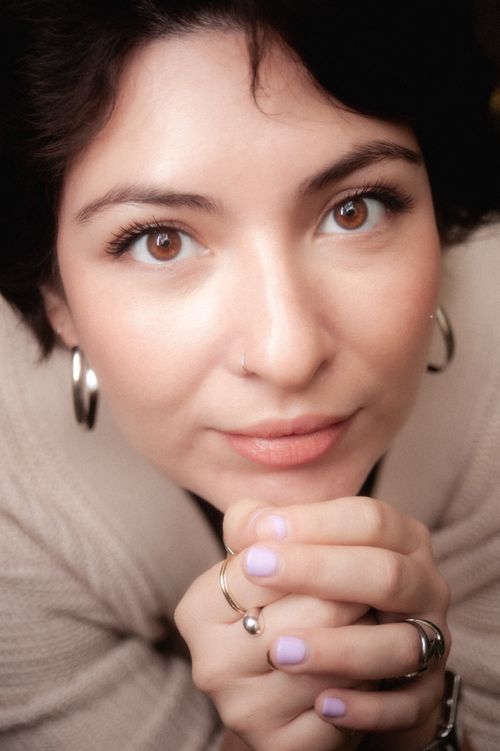 Free Captivating portrait of a woman with short hair and brown eyes, resting hands on chin. Stock Photo