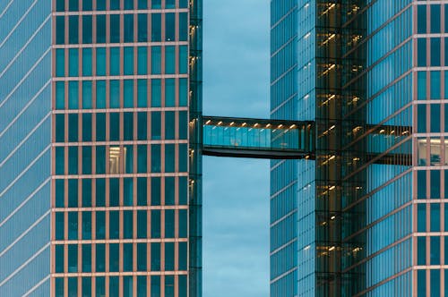Two tall buildings with glass windows and a bridge