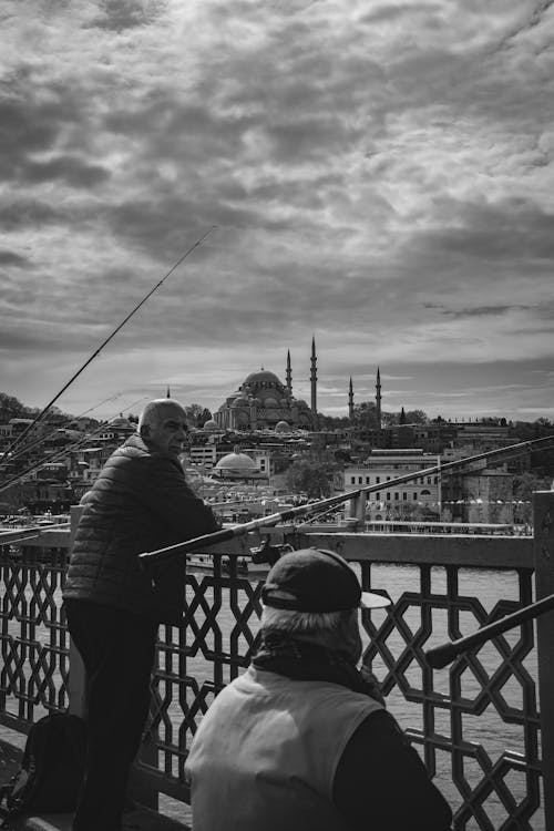 A man is fishing on a bridge over the water