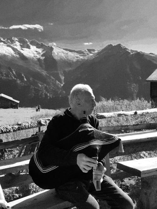 Free A man sitting on a bench in front of mountains Stock Photo