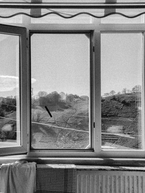 A black and white photo of a window with a view