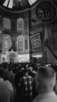 Black and white photo of a crowd praying inside Hagia Sophia Mosque, Istanbul, emphasizing spirituality.
