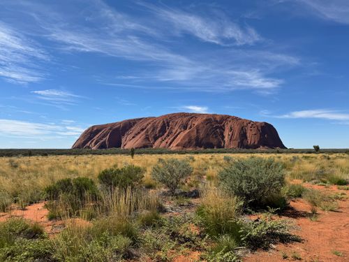 Free Breathtaking view of Uluru surrounded by Australian desert landscape under a bright blue sky. Stock Photo