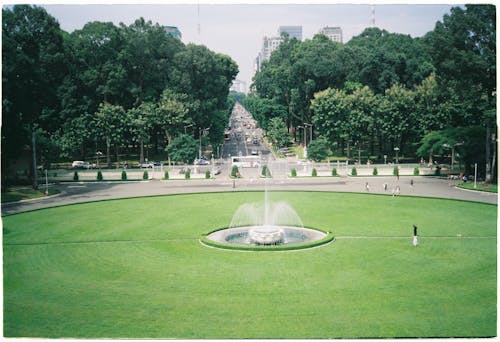 A green grassy area with a fountain in the middle